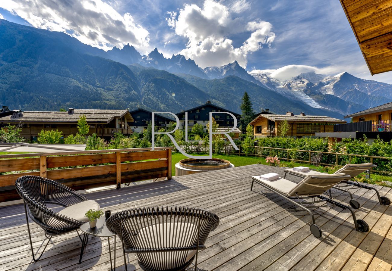 Chalet les Trois Soeurs a une terrasse à deux niveaux avec jacuzzi en bois et mobilier d'extérieur