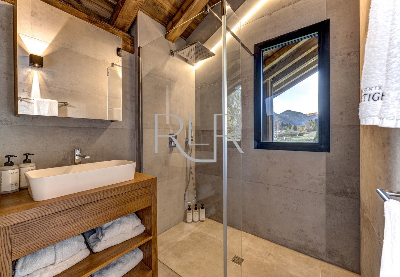 Bedroom 5 of Chalet les Côtés du Lavancher  has an ensuite shower and basin with mountain views.